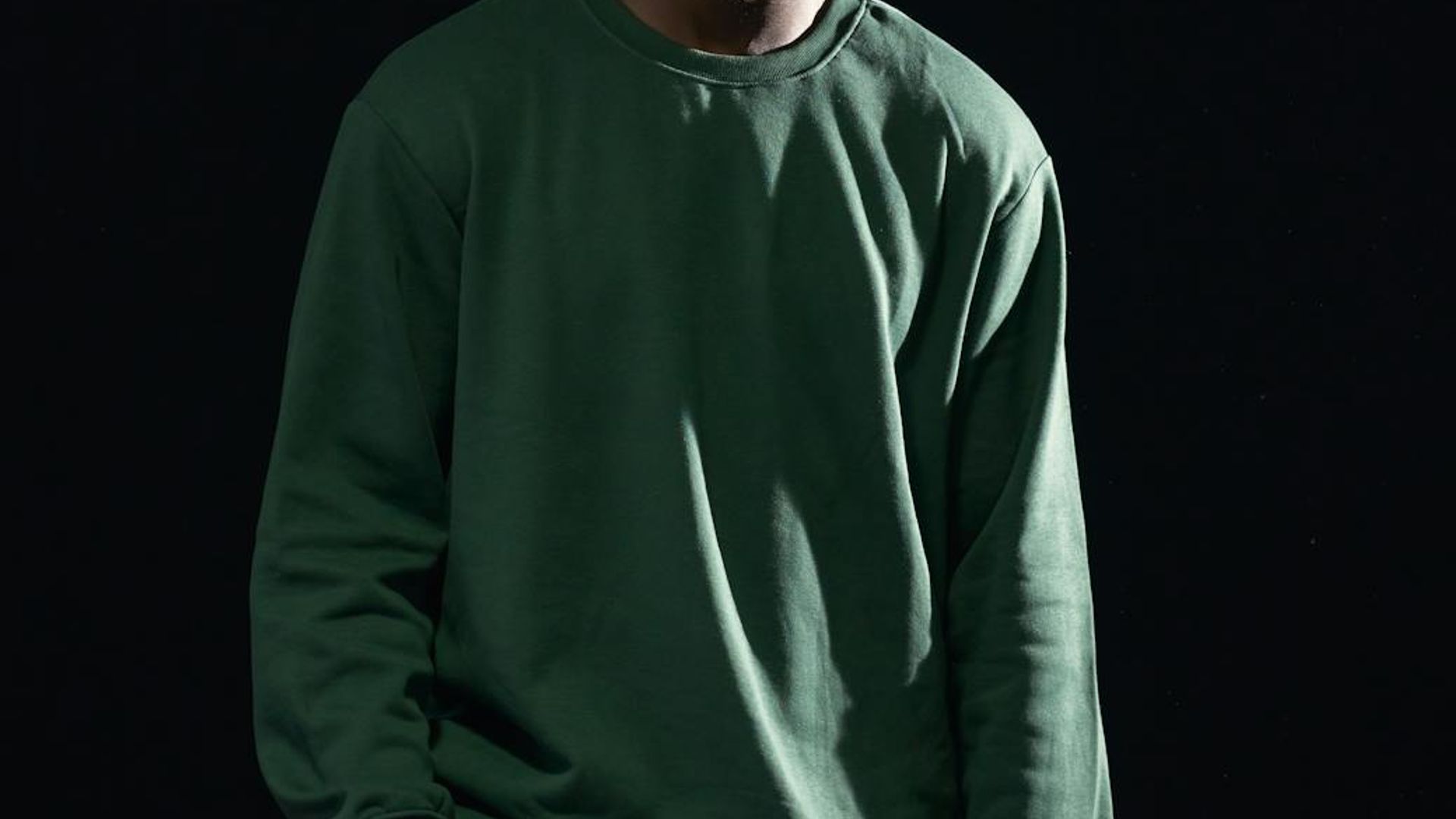 Man standing in a powerful static pose in a minimalist room.